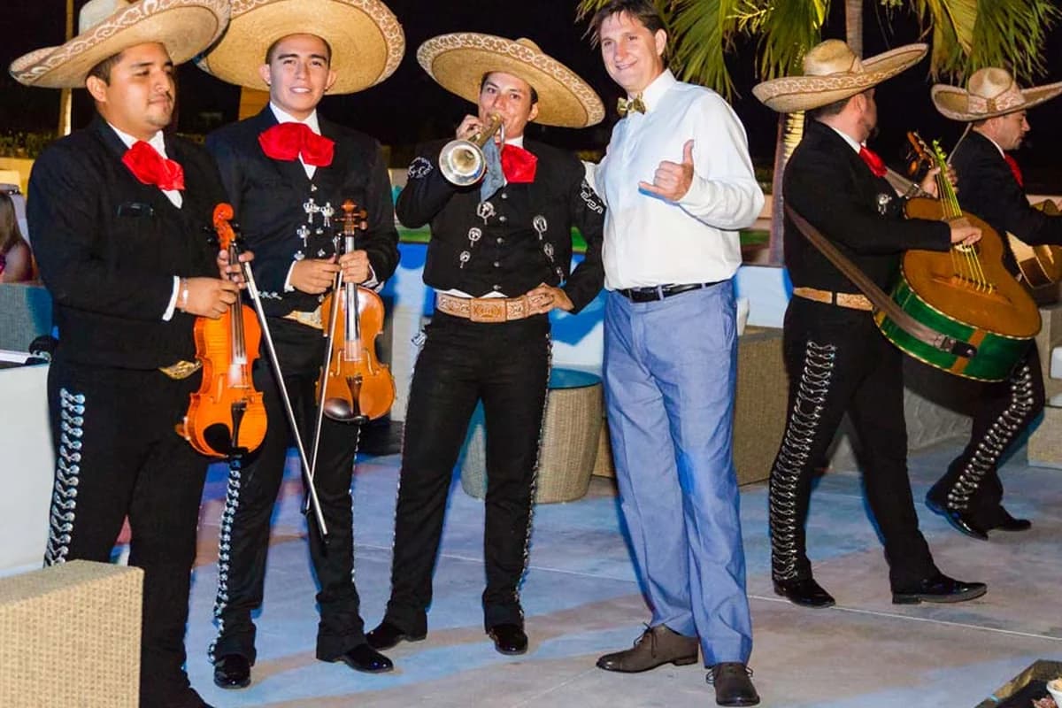 A mariachi band posing with a guest at an evening celebration