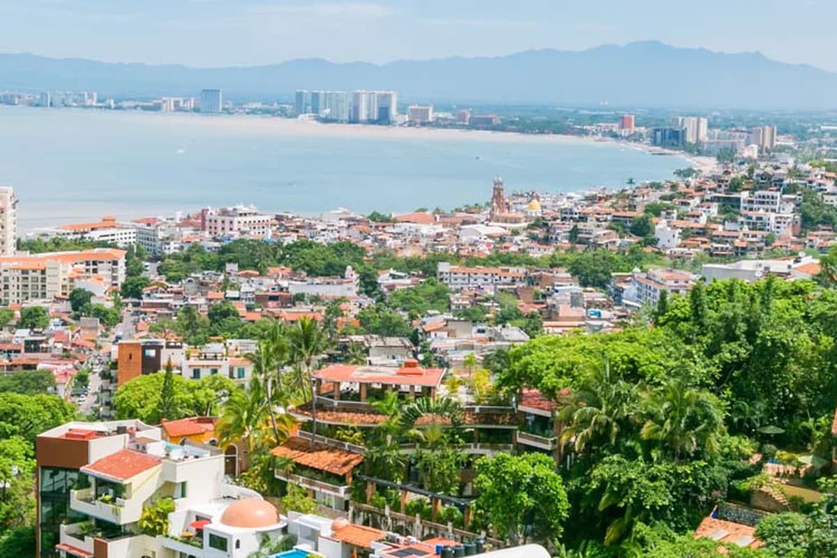 Aerial view of Puerto Vallarta's Banderas Bay coastline, with the old town's red-tile rooftops between the mountains and the water