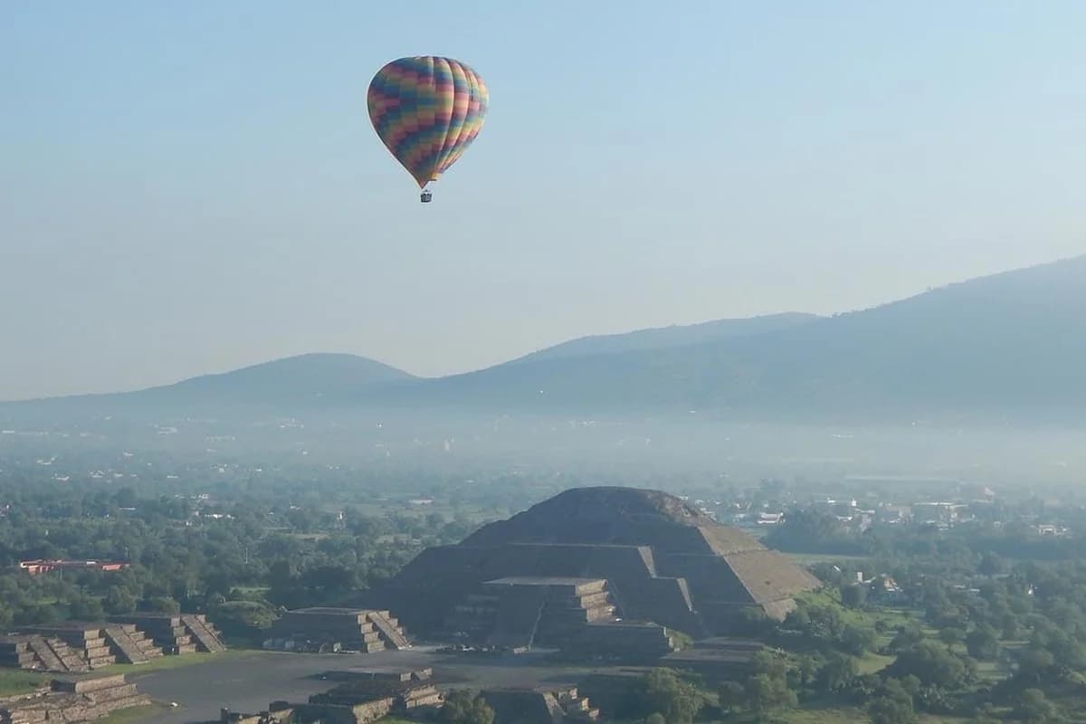 A colorful hot air balloon floating over the Pyramid of the Moon at the Teotihuacan archaeological site near Mexico City